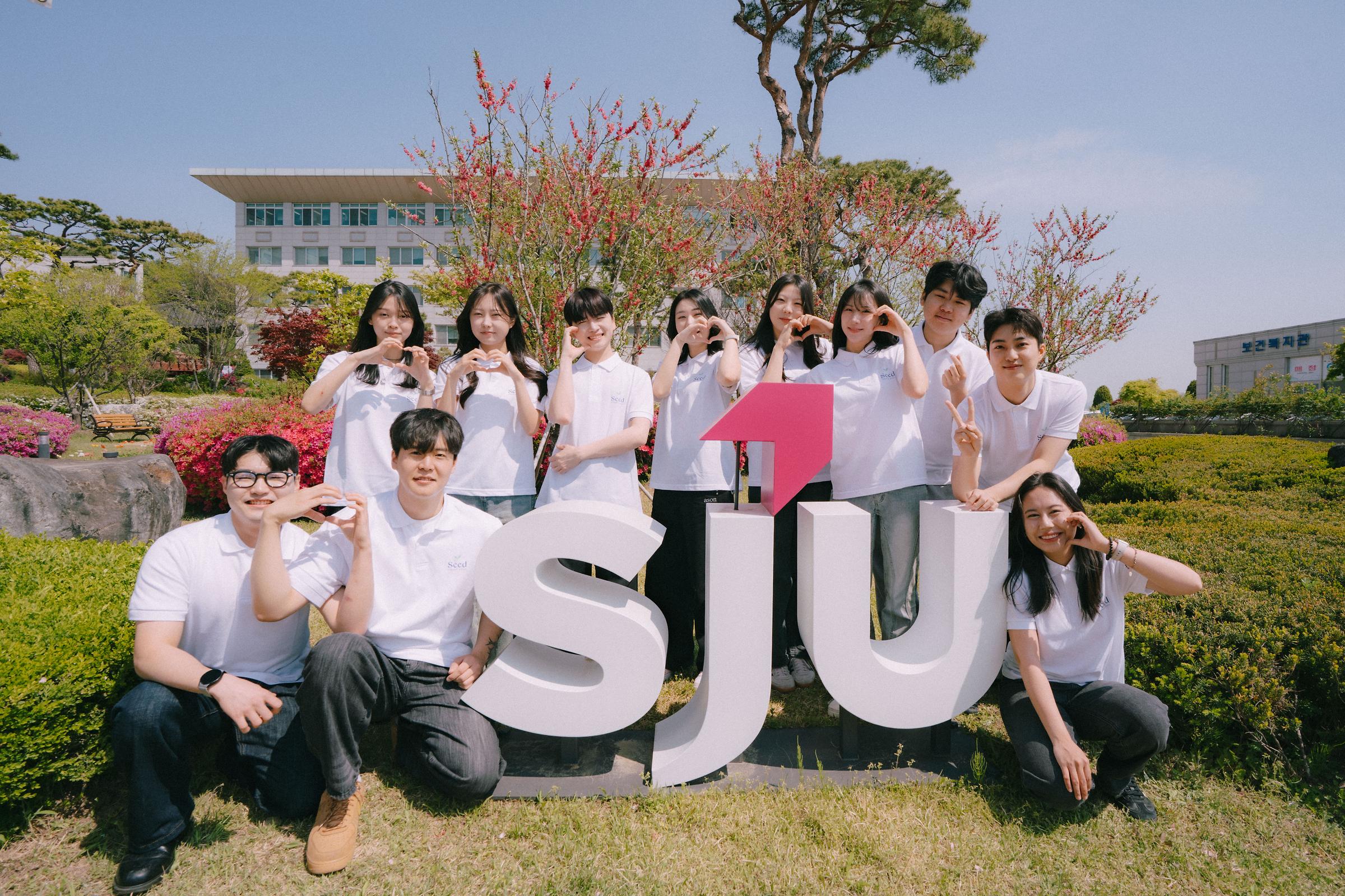 홍보대사 단체사진 11명이 sju 조형물을 둘러싸고 손하트를 하고 있음